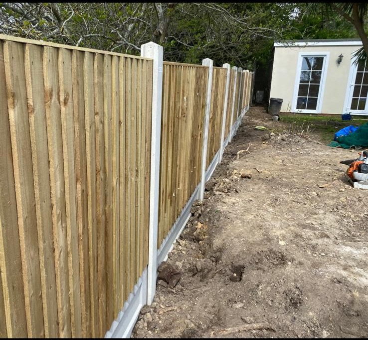 New close-board fence being installed with concrete posts