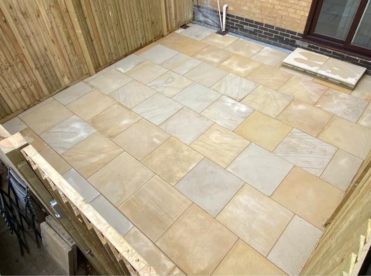 Sandstone patio laid in front of a close-board fence