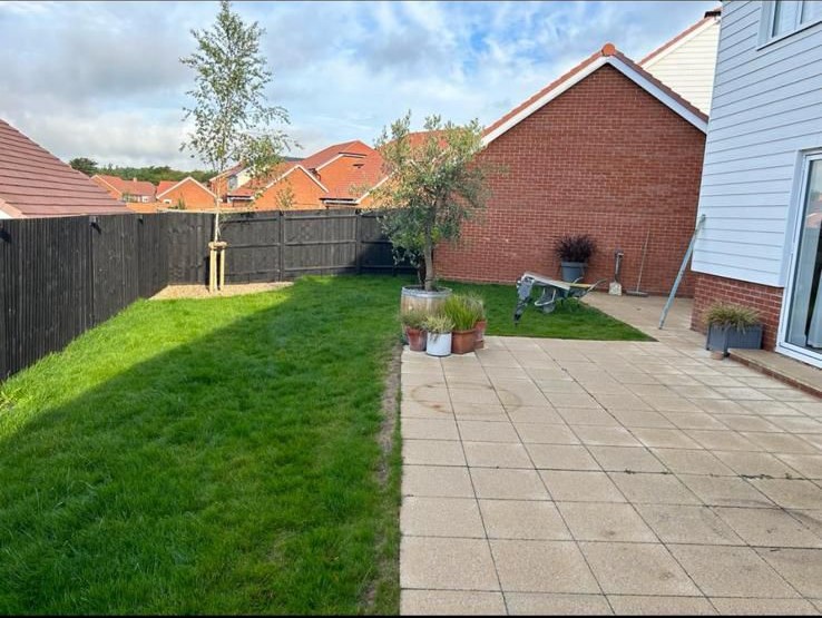 New fence panels and lawn alongside a brick house