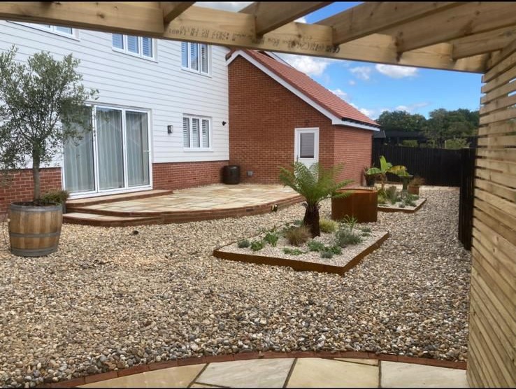 Patio with timber pergola and planted bed beside a house